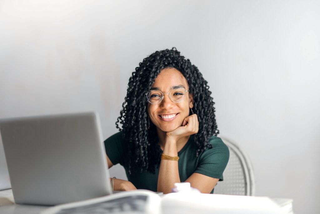 A happy woman sitting in front of her grey laptop